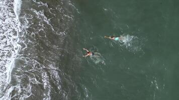 Top view of people swimming in blue water on cloudy day. Clip. Beautiful blue sea with waves and floating people. Tourists swim and relax on beautiful sea with blue water photo