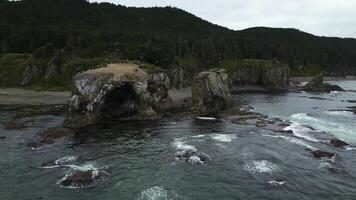 Top view of amazing coast with rocks and erosion. Clip. Through rocks with flying gulls on seashore. Fantastic landscape with rocks and seagulls on shore of North Sea on cloudy day photo