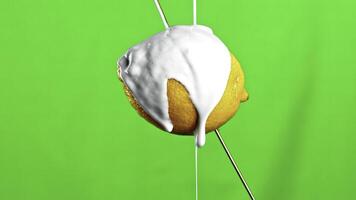 Fresh yellow lemon isolated on a green background. Stock clip. Pouring white paint on a lemon fruit with drops falling down. photo