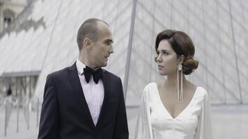 hermosa elegante Pareja de amantes caminando en antiguo ciudad. acción. lujoso Pareja camina en amor en París. Pareja en elegante trajes camina en antecedentes de vaso pirámide foto