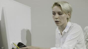 A young woman in a white coat. Stock footage.An employee in a company with a short haircut who shows her project. photo