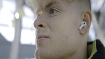 Close-up of man with headphones on street. Action. Young man with headphones looks into distance. Inspiring music in headphones on sunny day photo