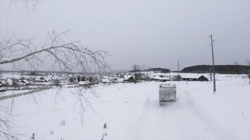 Top view of landscape of driving truck in village in winter. Clip. Truck drives into old village on cloudy winter day. Beautiful landscape of winter village photo