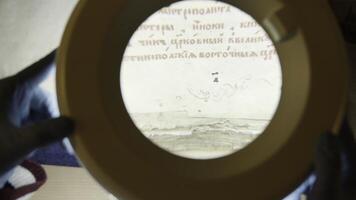 A large magnifying glass lamp that shines on an old letter. Stock footage.An old paper covered with Old Russian letters in the archive, which is examined by experts. photo