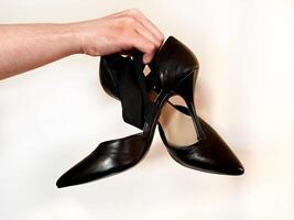 Man's hand holding pair of heels shoes. photo