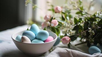 ai generado un blanco cuenco lleno con azul y rosado huevos sentado en parte superior de un mesa siguiente a un manojo de flores foto