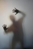 Man with Raised Hands Silhouette Behind Frosted Glass photo