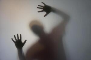 Man with Raised Hands Silhouette Behind Frosted Glass photo