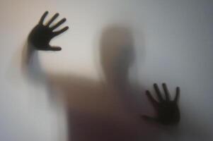 Man with Raised Hands Silhouette Behind Frosted Glass photo