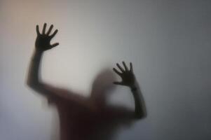 Man with Raised Hands Silhouette Behind Frosted Glass photo