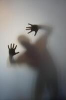 Man with Raised Hands Silhouette Behind Frosted Glass photo