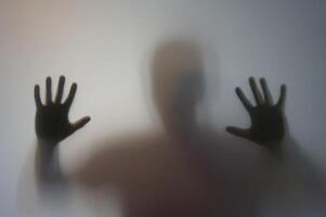 Man with Raised Hands Silhouette Behind Frosted Glass photo