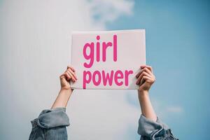 AI generated cropped view of woman holding sign with girl power lettering on sky background photo