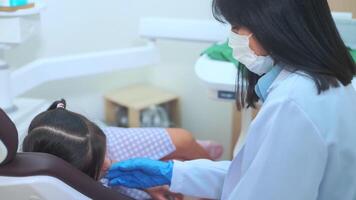 una niña linda con los dientes examinados por un dentista en una clínica dental, un chequeo dental y un concepto de dientes sanos video