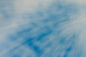 Abstract horizontal spotted background of blurred blue sky with clouds and rays of light in motion. Design element with copy space. photo