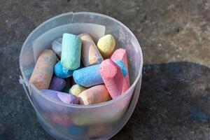 Multi colored crayons in an old broken bucket on a concrete background. photo