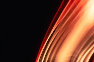 Abstract red-orange uneven diagonal waves glowing on black background with space for text. photo