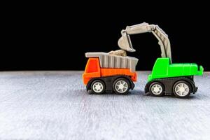 Construction work concept of toy model truck backhoe on the road and black color background photo