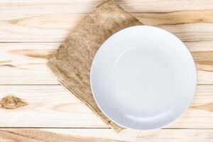 Empty white plate on Sack wood table for copy space and texture photo