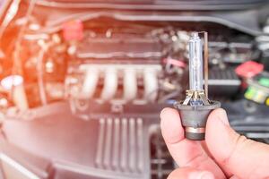 Close up car headlights xenon Lighting Equipment in hand a man with engine room for maintenance concept of car photo