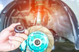 Close up hand a man and bearing for shock absorber of car  suspension repair concept and maintenance with sunset light background photo