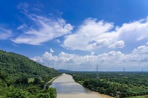 naturaleza ver rápidos río agua y montaña con ligero azul cielo y Alto voltaje electricidad polos foto