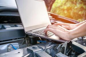 Close up hand Technician use computer Analyze car problems The parking lot on the side of the road photo