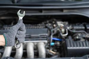 Servicio concepto de coche técnico es utilizando un llave inglesa para reparar coche foto