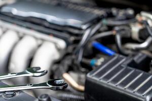 Wrench on the engine compartment Mechanic checking and fixing a broken car in car service garage photo