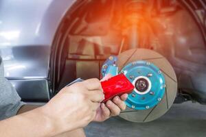 Hand Technician apply grease on new brake pad and change in caliper with car wheel basic service concept of car with run stop system photo