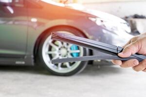 Close up hand Technician with left rubber the wiper for glass car in garage shop service and maintenance and car in background photo