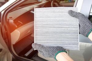 Close up Air filter in hand service concept in air condition system of car and inside car blur background photo