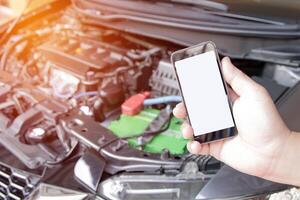 Close up smartphone white display in hand a man for texture and car engine room background in service concept photo