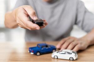 Close up hand of man holding and push remote control for lock and Un-lock car concept model toy a car in blur background photo