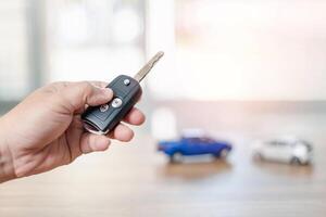 Close up hand of man holding and push remote control for lock and Un-lock car concept model toy a car in blur background photo