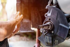 Home service concept drive shaft of car wheel a man checking bearing and adding grease in checking maintenance period of car for safety in travel and photo