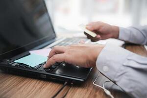 A man typing on keyboard laptop and hold a post it note paper  written for memory and working in office photo