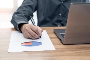 Business man working and analyzing on document data graph with laptop computer calculate for new project of business strategy at workplace. photo