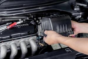 un hombre abierto cubrir de aire filtrar para cambio nuevo aire filtrar de coche motor comparado a el antiguo parte en motor habitación hogar Servicio coche concepto foto