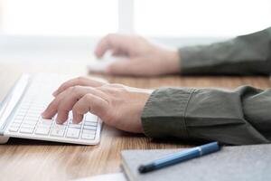 Hand a man typing on keyboard on wood table working concept in office photo