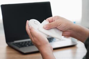 Close up hand a man cleaning and disinfection of workspace. Disinfecting wipes to wipe surface of desk , laptop, mouse at office. Stop the spread photo