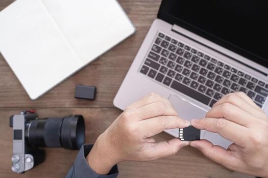 Close up memory card of camera in hand a man and camera and photography equipment on table photo