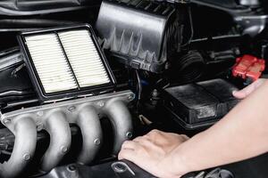 Close up new air filter of car in engine room and a man remove old air filter Basic service concept of car photo