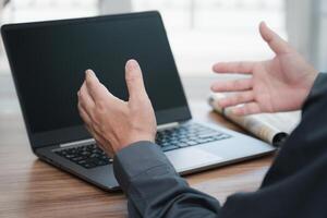 Action working concept  Close up hand a man Describing tasks in an online meeting with laptop computer and document on wood table work in office photo