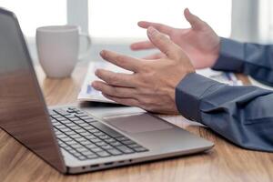 Action working concept  Close up hand a man Describing tasks in an online meeting with laptop computer and document on wood table work in office photo