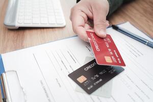 Close up hand a man hold credit cards on insurance document for payment of Annual car insurance expenses that must be paid regularly instead of using cash photo