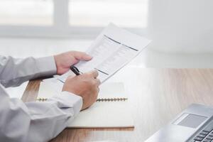 A man of car service center write on the clipboard paper check service list in office with repair part of car and laptop computer on wood table photo