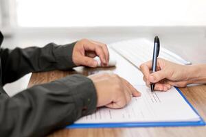 Women sign contact  in document  with Insurance agent on clipboard while examining working process Insurance concept photo