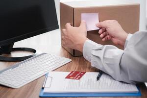 Man paste the pink note paper on the side of the box to mark it and checklist credit card and use computer desktop for stock check photo