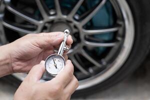 Home car basic check  close up A man hold air pressure gauge check tire air pressure in service concept photo